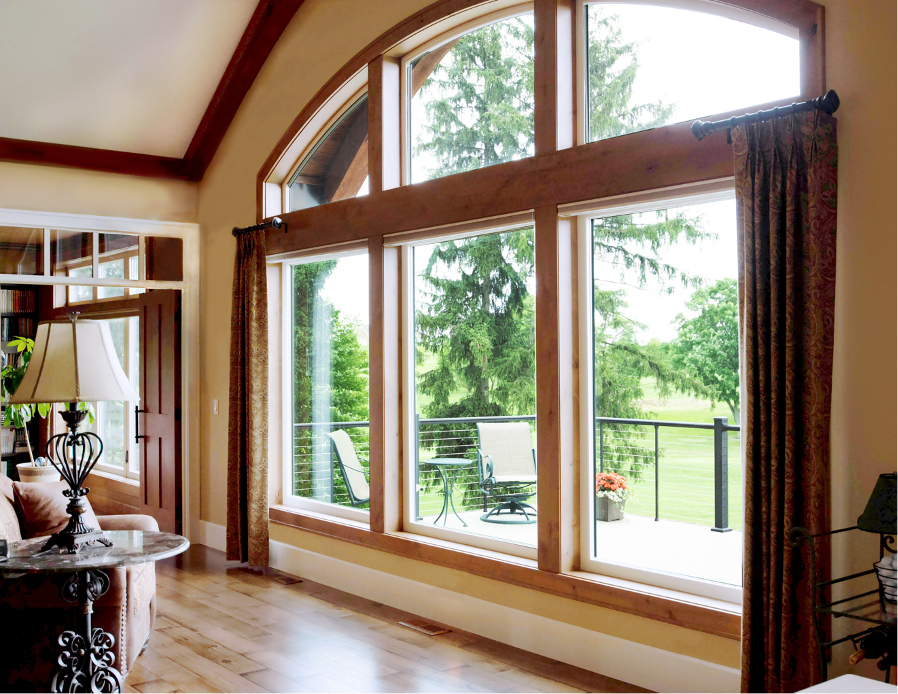 an interior photo of a 3-panel window section with a wood frame and brown curtains pulled back