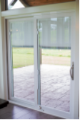 a white patio door leading outside to the patio with blinds inside the glass
