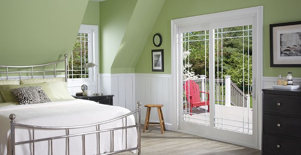 a photo of a pastel green painted bedroom with a white patio door with double prairie glass